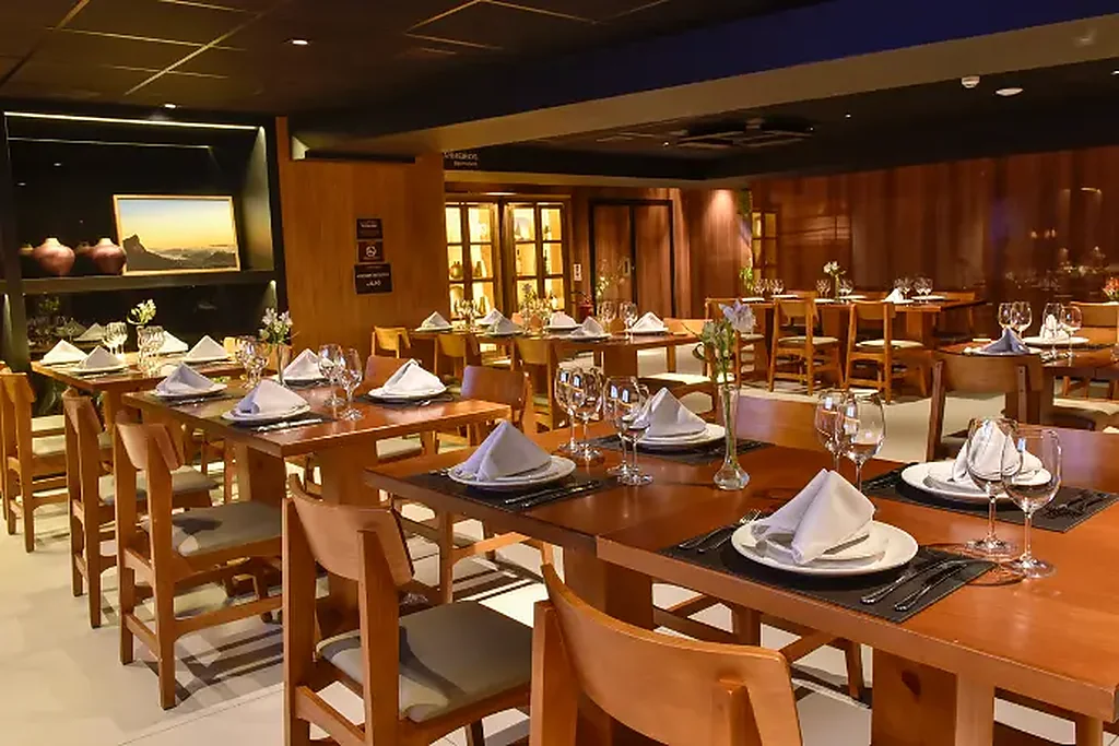 Mesas longas postas com guardanapos brancos, taças e talheres para o jantar